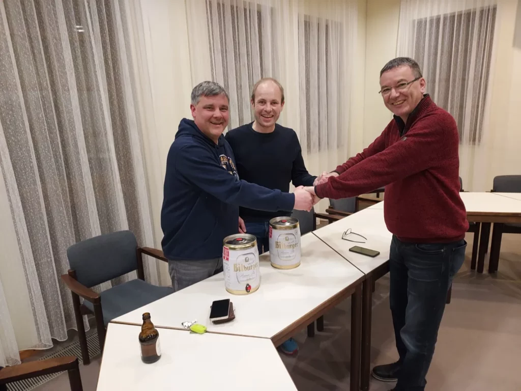 Drei Männer geben sich die Hand bei einem Treffen