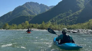 Zwei Teilnehmer beim Wassersport im Boot auf einem Fluss vor der Berge