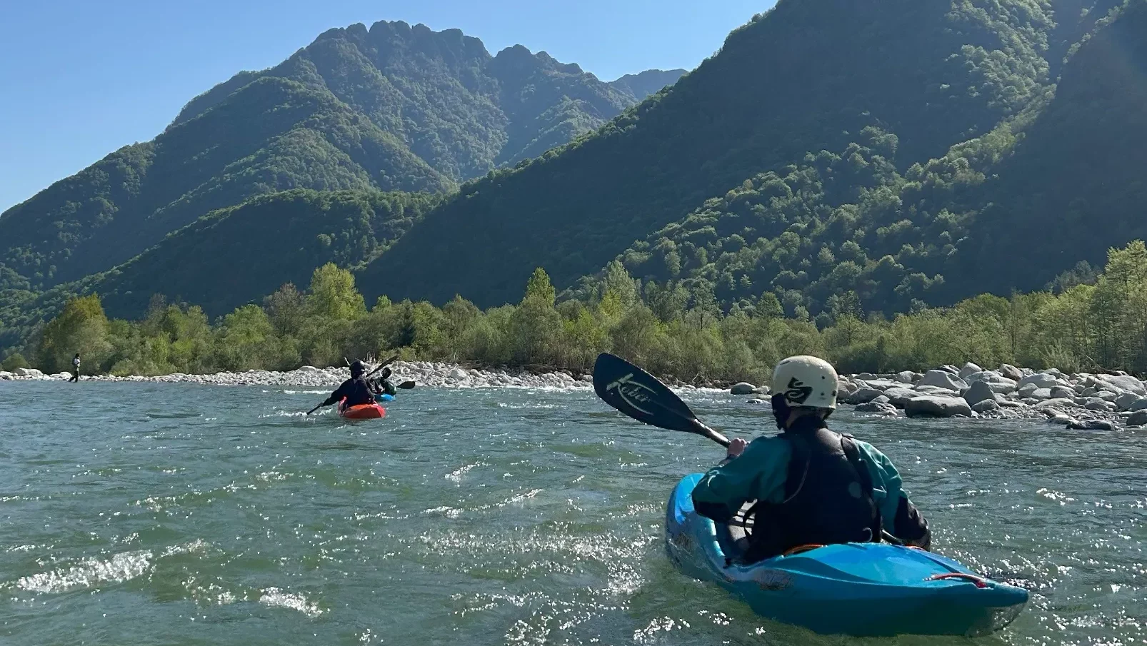 Zwei Teilnehmer beim Wassersport im Boot auf einem Fluss vor der Berge